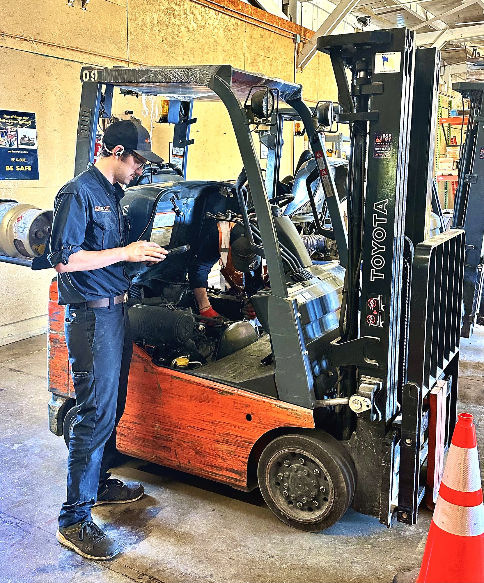 Forklift technician inspecting an aging warehouse forklift to evaluate whether it should be repaired, rehabbed, or replaced