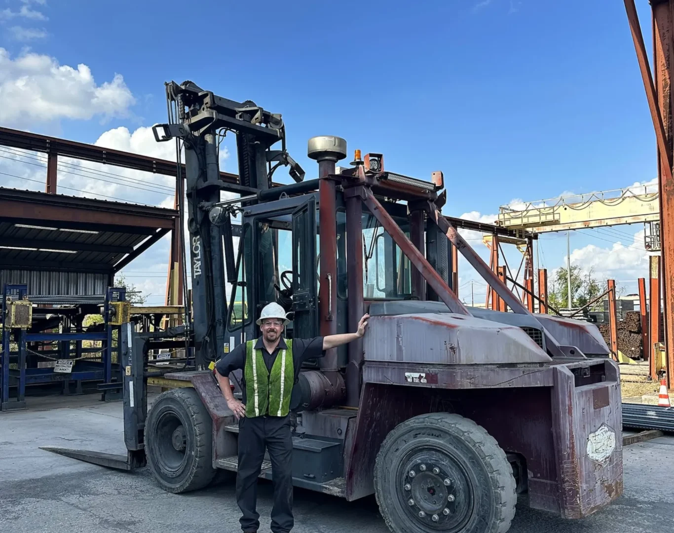 R&R Lift technician beside a large forklift in an outdoor yard